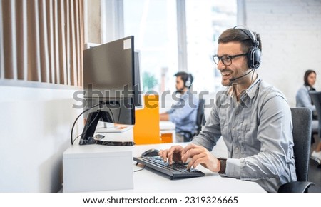 Friendly service agent using computer and talking to customer in call centre. Royalty-Free Stock Photo #2319326665