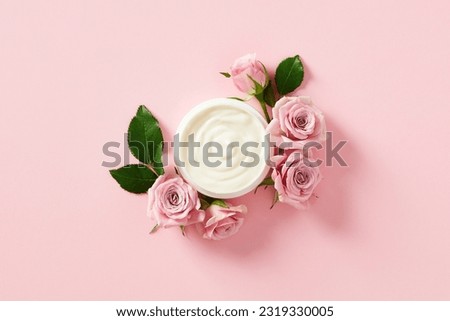 Jar of moisturizer cream with rose petals on pink background. Flat lay, top view.
