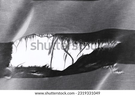 hanging teared rag spread isolated on black background , can use like a background or any texture. hole in the tissue. Unbleached beige fabric with torn stitch, hole and loose threads Royalty-Free Stock Photo #2319331049