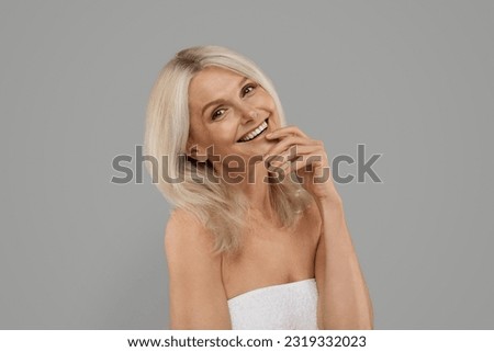 Mature Beauty Concept. Portrait Of Happy Elderly Woman With Beautiful Flawless Skin Standing Wrapped In Bath Towel Over Grey Background, Attractive Senior Female Smiling At Camera, Copy Space Royalty-Free Stock Photo #2319332023