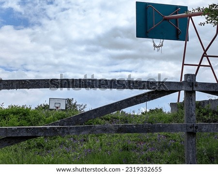 Basketball, white wooden boards. Red post. Net. Grey fence. Rivals, concept. White sky. Outside. Framed look.