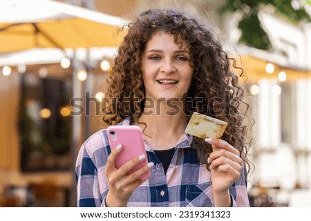 Lovely woman using credit bank card smartphone while transferring money, purchases online shopping, order food delivery, booking hotel room. Happy girl tourist walking in urban city street outdoors