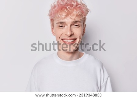 Portrait of handsome pink haired man dressed in casual clothes smiles gladfully concentrated into camera expresses positive emotions isolated over white background. People and face expressions concept Royalty-Free Stock Photo #2319348833