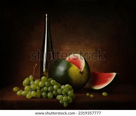 still life with a cut red watermelon with green grapes and a decorative bottle on the table on a dark background