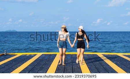 Two women friends or couples relaxing in the sea and walking at tropical beach travel summer holidays. Female tourists enjoy traveling to exotic nature in their leisure time. Friendship concept