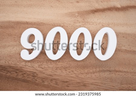 White number 9000 on a brown and light brown wooden background.