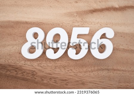 White number 8956 on a brown and light brown wooden background.