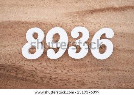 White number 8936 on a brown and light brown wooden background.