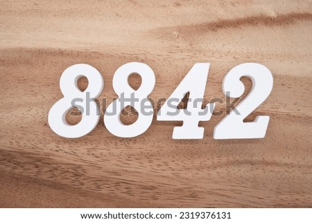 White number 8842 on a brown and light brown wooden background.
