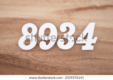 White number 8934 on a brown and light brown wooden background.