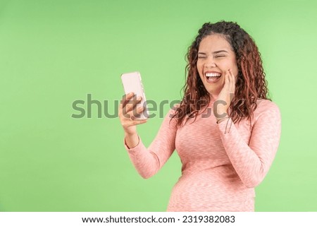 Young woman laughing while making a video call, on a green background