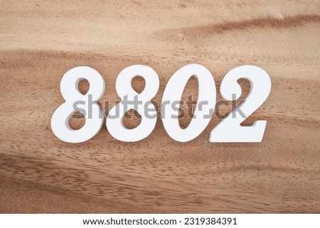 White number 8802 on a brown and light brown wooden background.