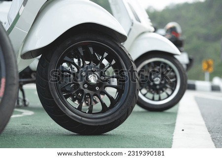 Close-up of wheels of a scooter motorcycle parked on a beautiful road in the daytime.	 Royalty-Free Stock Photo #2319390181