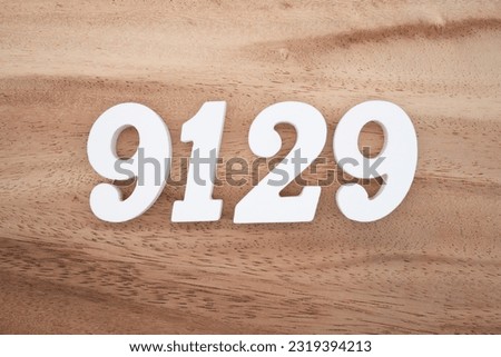 White number 9129 on a brown and light brown wooden background.