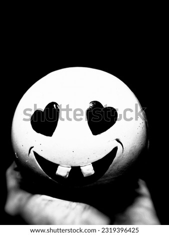 A smiling doll with two teeth is smiling on someone's hand.