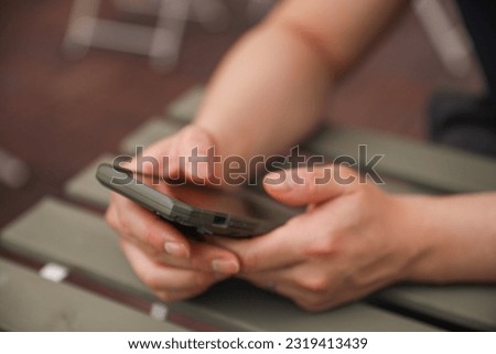 A person holding a phone at the table, symbolizing connectivity, communication, and the integration of technology in daily life
