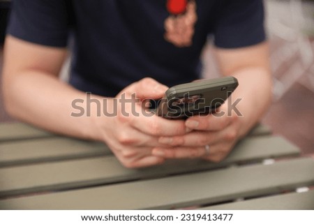 A person holding a phone at the table, symbolizing connectivity, communication, and the integration of technology in daily life