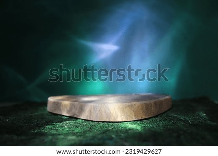 Sawn tree podium, on green moss, on a dark background. Beautiful northern lights on the background. Presentation of products. High quality photo