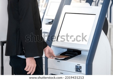Well-dressed Businessman passenger using self service machine and help desk kiosk at airport terminal for check in, print boarding pass or buying ticket. Business travel and holiday trip concepts Royalty-Free Stock Photo #2319431213