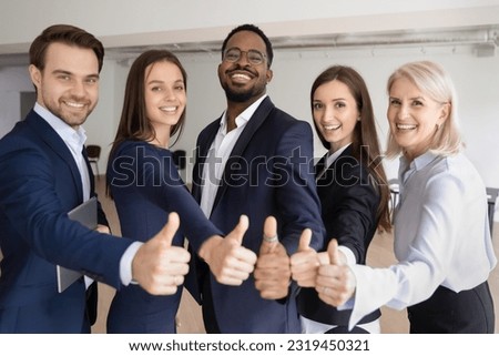 Happy multiethnic different aged business team making thumbs up. Office staff, young and mature workers, employees, interns and mentor showing like at camera. Corporate group portrait