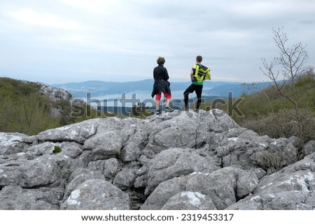Two hikers on viewpoint with panoramic view of Kotor bay around Pestingrad (Derinski Vrh), Montenegro, Adriatic Mediterranean Sea