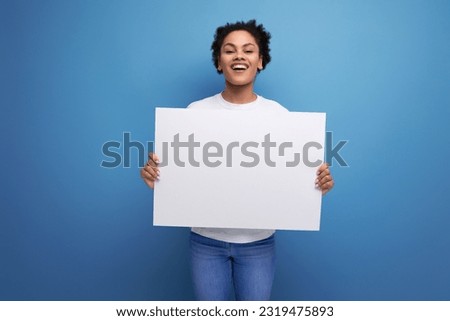 young pretty hispanic business music lover woman in a white t-shirt holding a white board with a mockup for advertising