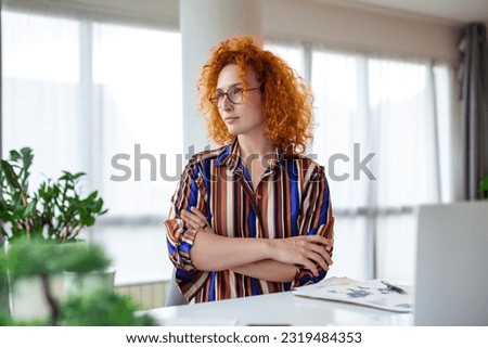 Young female employee stand at desk in office look in distance thinking or visualizing career success. Happy businesswoman plan or dream at workplace. Business vision concept.