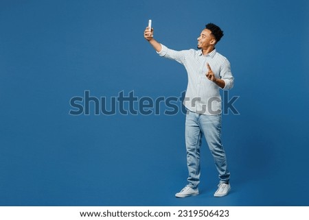 Full body young man of African American ethnicity wear casual clothes shirt doing selfie shot on mobile cell phone post photo on social network isolated on plain dark royal navy blue background studio