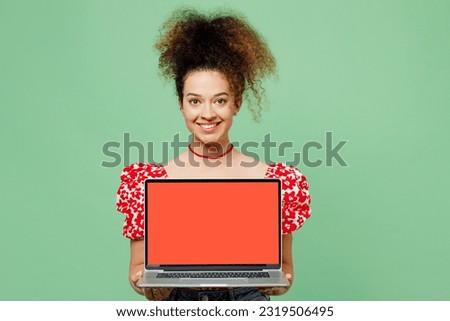 Young smiling happy IT woman she wearing casual clothes red blouse hold use working on laptop pc computer with blank screen workspace area isolated on plain pastel light green color background studio