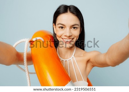 Close up young woman wears swimsuit hold lifeguard inflatable ring do selfie shot mobile cell phone near hotel pool isolated on plain pastel blue background. Summer vacation sea rest sun tan concept