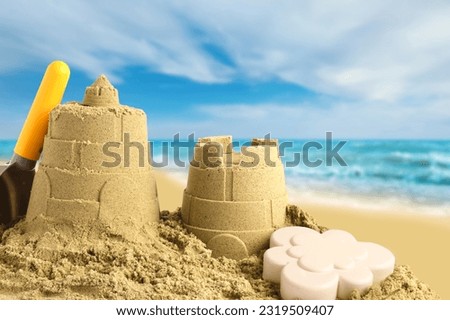 Sand castles with toys on ocean beach, closeup. Outdoor play