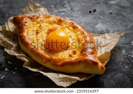 Ajarian Khachapuri, filled with cheese and topped with egg yolk, traditional Georgian Khachapuri with cheese-filled bread on Dark Rustic Background Royalty-Free Stock Photo #2319516397