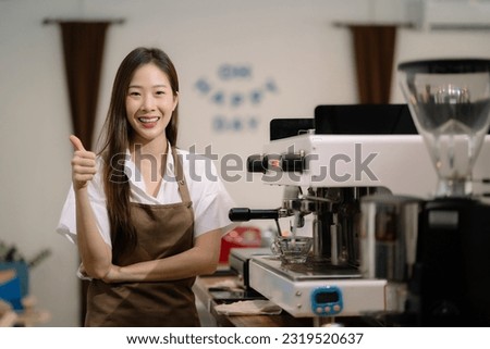 Asian female barista wear apron at counter bar with smile face, cafe service concept, owner business start up.