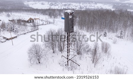 Top view of the snowy winter landscape of the town. Wooden water tower. Russian province.