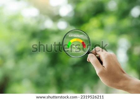 hand holding a magnifying glass to check the  good air quality and clean outdoor air quality safe from pollution dust PM 2.5 Royalty-Free Stock Photo #2319526211