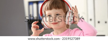 Portrait of cute girl in headphones watching cartoons using laptop computer