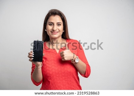 Indian woman showing smartphone screen and thumps up on white background. Royalty-Free Stock Photo #2319528863
