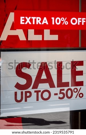 Advertising of the annual period of discounts in the store, information about sale in glass shop window with reflection of people and shopping mall.