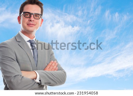 Young business man with grey suit over clouds background. With arms crossed