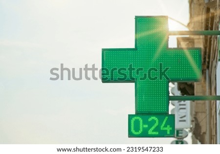 Green cross pharmacy sign on the building with neon lights. Selective focus. Symbol of health and pharmacy products. Stock photo with empty space for text.                              