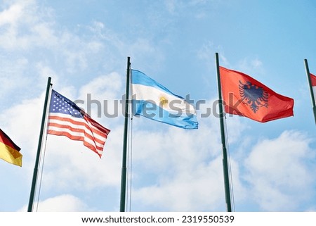 USA, Argentina and Albania flags on blue sky