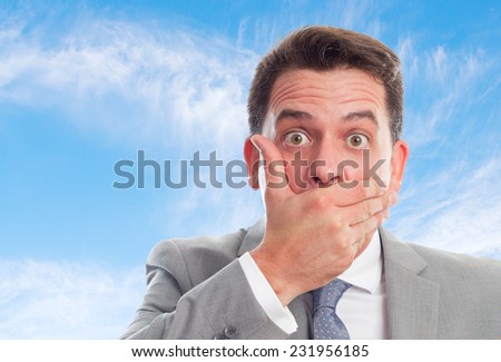 Young business man with grey suit over clouds background. Looking surprised