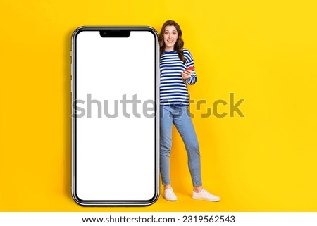 Full size photo of attractive young woman gadget excited big smartphone dressed stylish striped look isolated on yellow color background