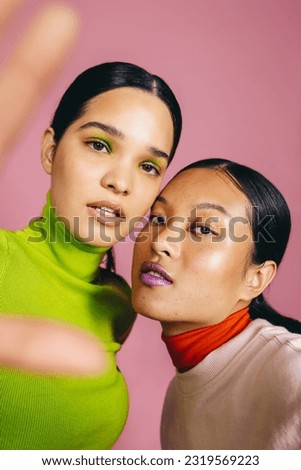 Two female friends taking a selfie while wearing flawless makeup. Looking at the camera with confidence, they embrace a radiant and vibrant lifestyle of skincare and beauty.