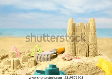 Sand castle with toys on ocean beach. Outdoor play Royalty-Free Stock Photo #2319571903