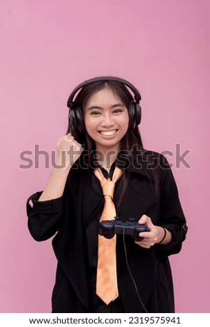A female gamer wearing headphones and using a controller to play video games. Winning a competition. Isolated on a pink background.