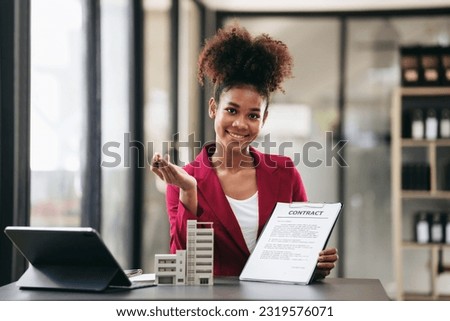 African american businesswoman in suit showing condominium model and contract document to presentation about renting or buying and insurance housing while working on tablet in workspace modern.