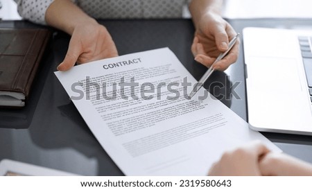Business people sitting and discussing contract in office, closeup. Partners or lawyers working together at meeting before signing papers. Teamwork and partnership