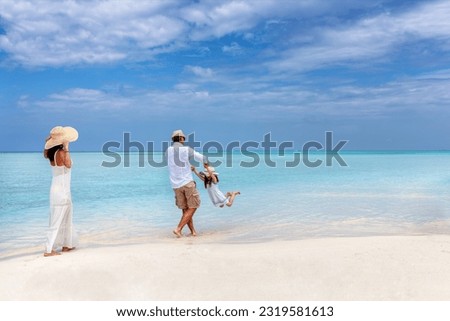 A happy family has fun in the turquoise ocean of a  tropical paradise beach in the Maldives during their holiday time Royalty-Free Stock Photo #2319581613