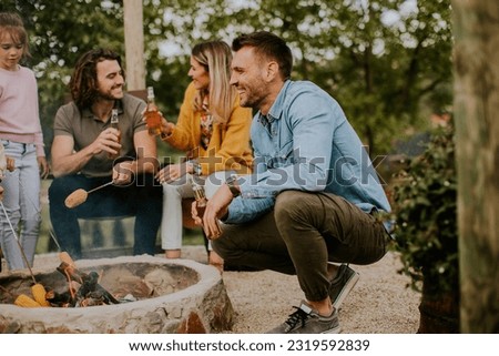 Group of friends having good time and baking corns in the house backyard Royalty-Free Stock Photo #2319592839